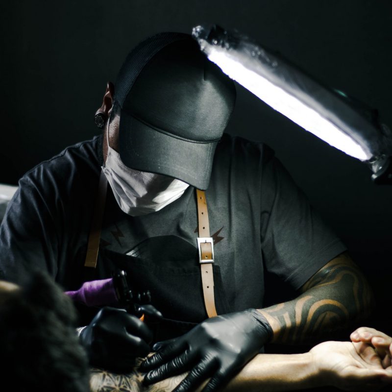 tattoo-artist-in-black-gloves-drawing-a-tattoo-on-a-person-s-1304468